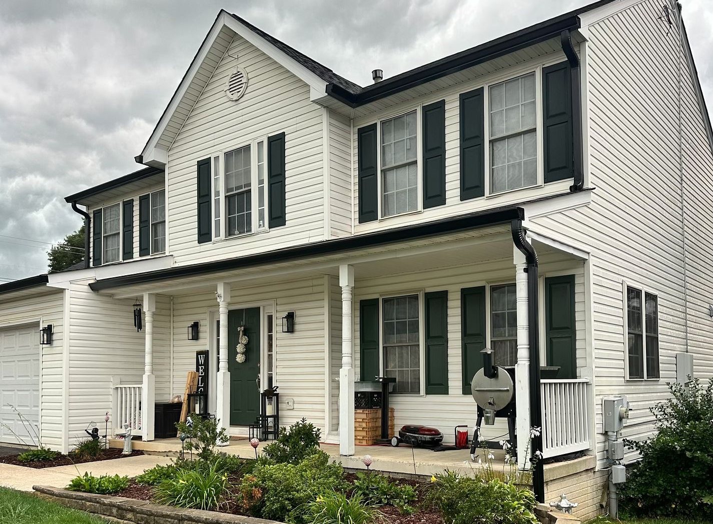 Two-story white colonial home with new black seamless gutters and downspouts installed by Kelly Home Improvements
