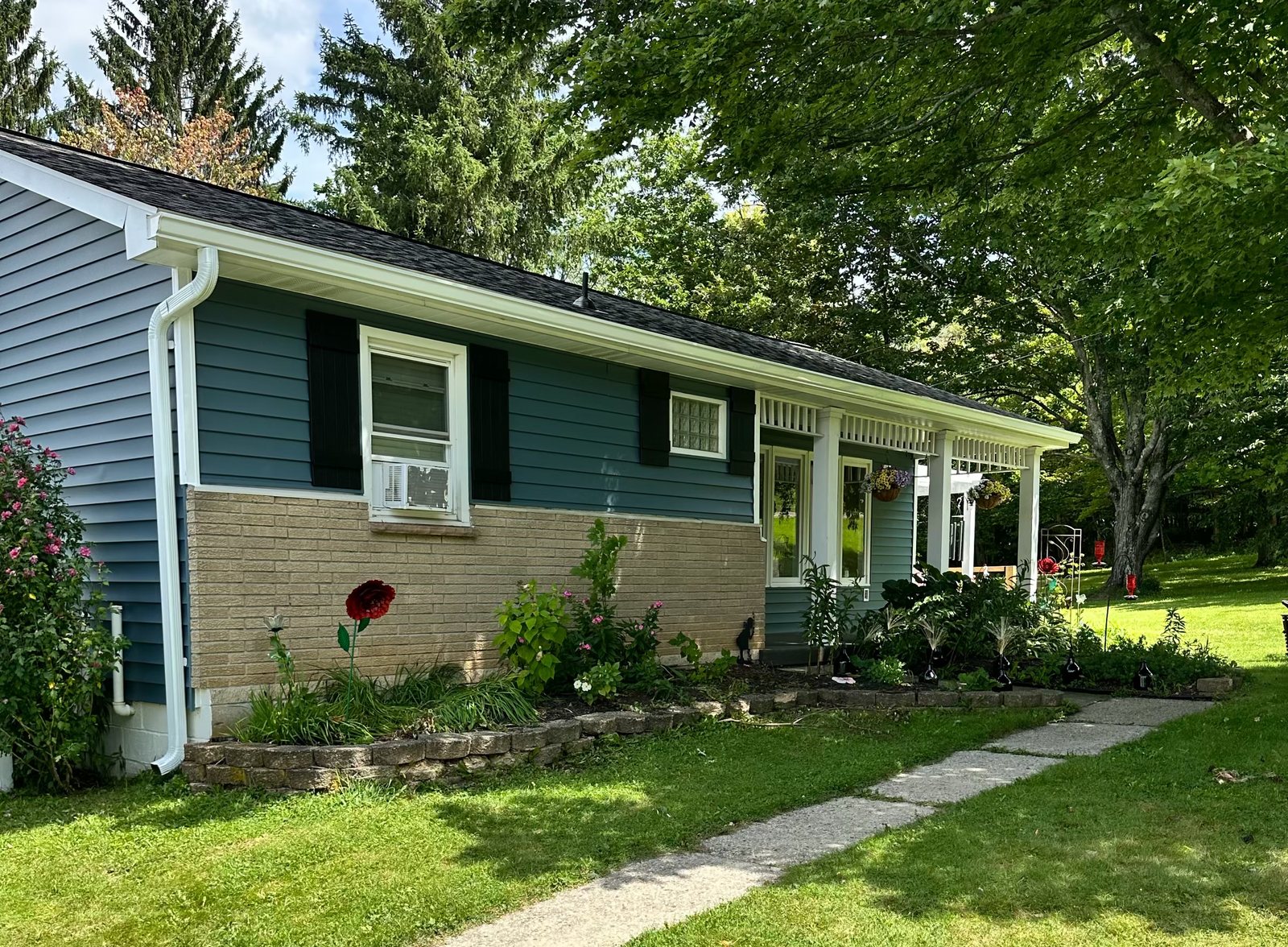 Ranch home with new blue vinyl siding, white trim and white gutters installed by Kelly Home Improvements