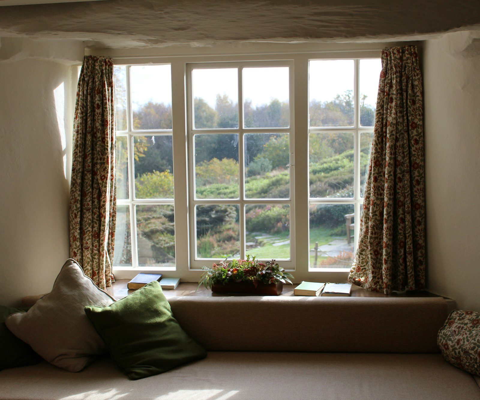 Bright window with a cushioned window seat looking out over green hills